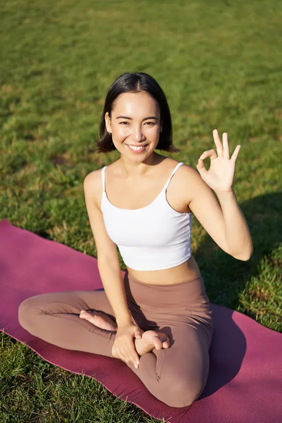 Portrait of asian woman sitting on rubber mat meditating showing