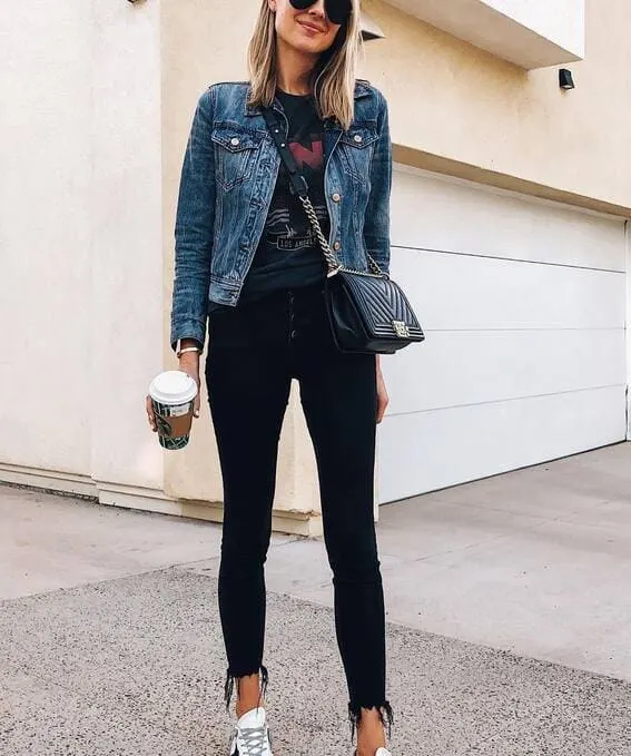 A woman wearing jeans, graphic T-shirt as well as black skinny jeans paired with sneakers. 