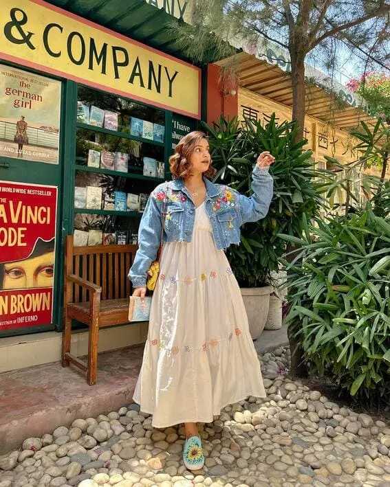 A woman wearing an embroidery denim jacket and White maxi dresses,