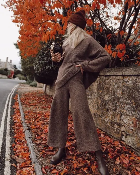 Woman in a cozy fall knit set with a beanie and ankle boots. 