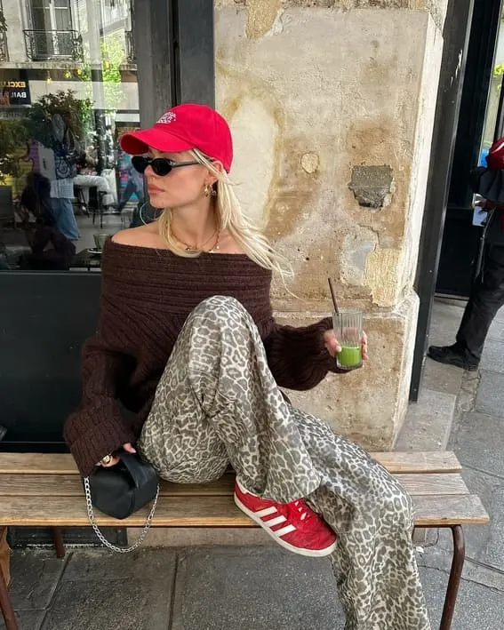 Woman in an edgy fall outfit with a red cap and leopard print pants. 