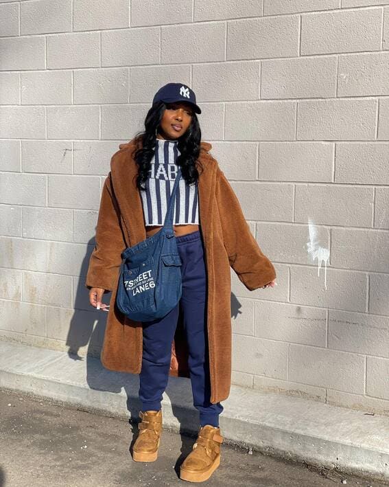 Woman in a sporty fall outfit with a teddy coat and baseball cap. 