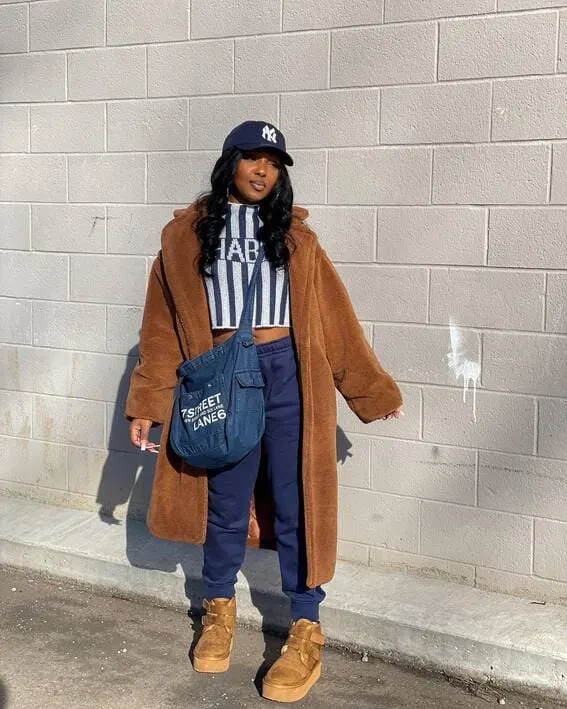 Woman in a sporty fall outfit with a teddy coat and baseball cap. 