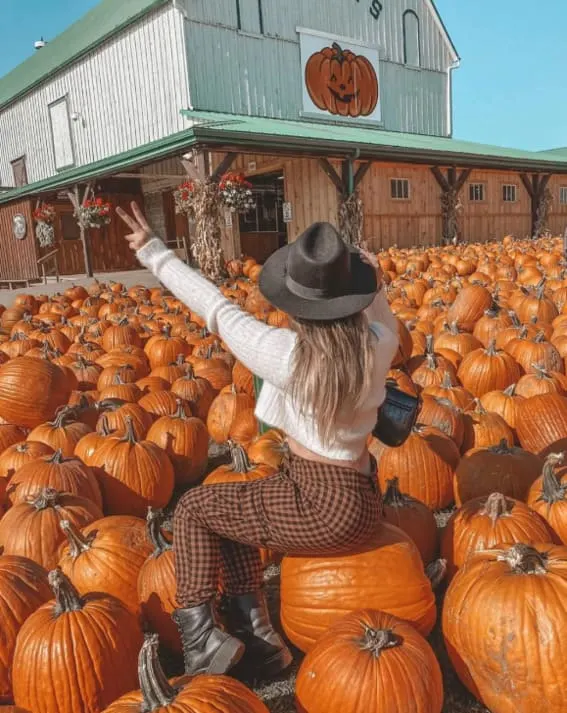 Woman in a cozy fall outfit with a wide-brim hat and plaid pants. 