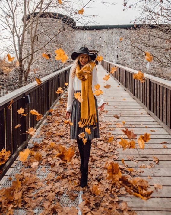 Woman in a classic fall outfit with a wide-brim hat and cozy scarf. 