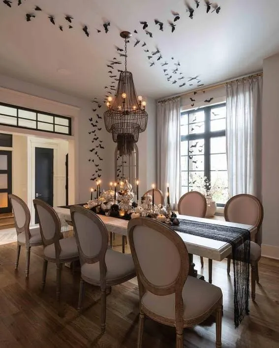 Elegant dining room adorned with bat decor and candlelit table setting.