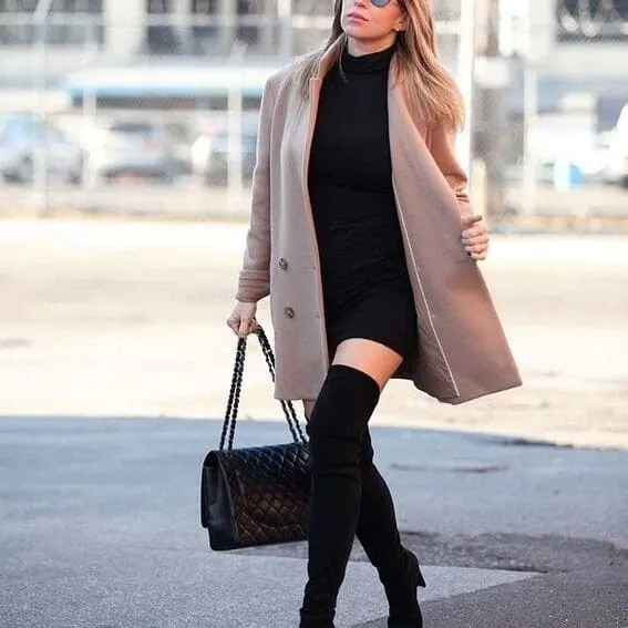 A woman in a black turtleneck sweater along with a camo coat as well as over-the-knee booties. 