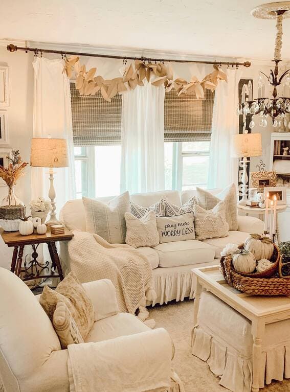 A cozy living room adorned with an oversized paper leaf garland hanging above the window, creating a soft and minimalist autumn vibe. 