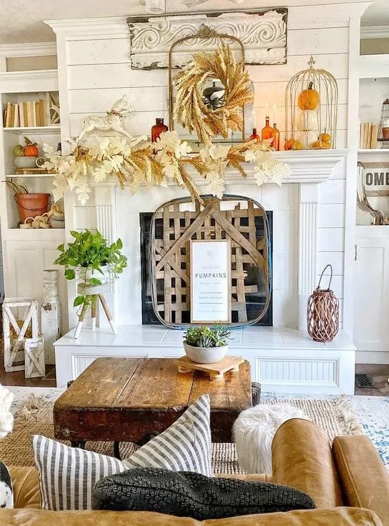 A rustic fall mantel adorned with a neutral-toned garland made of wheat stalks and paper leaves, creating an earthy and cozy autumn look. 