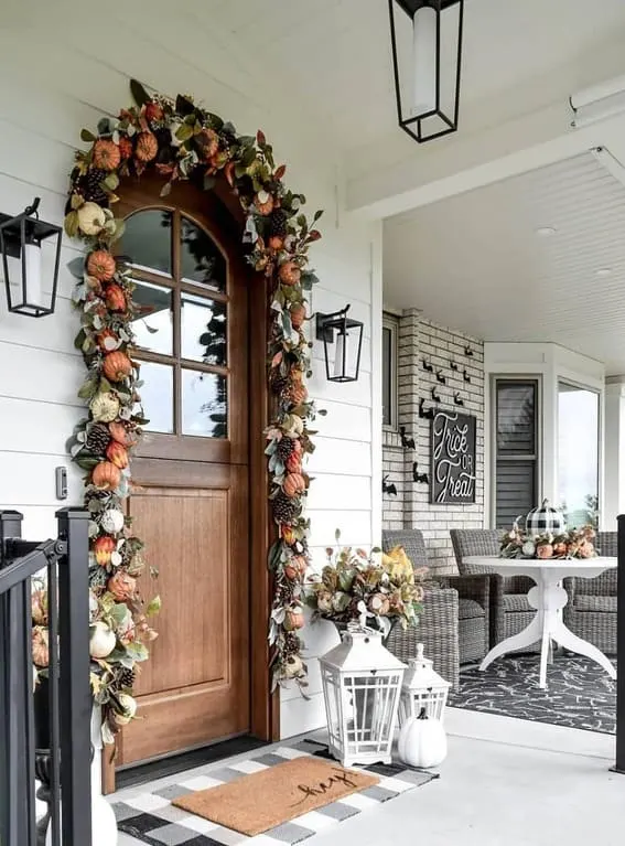 A beautifully crafted front door garland featuring pumpkins, pinecones, and eucalyptus, creating a welcoming autumnal entrance. 