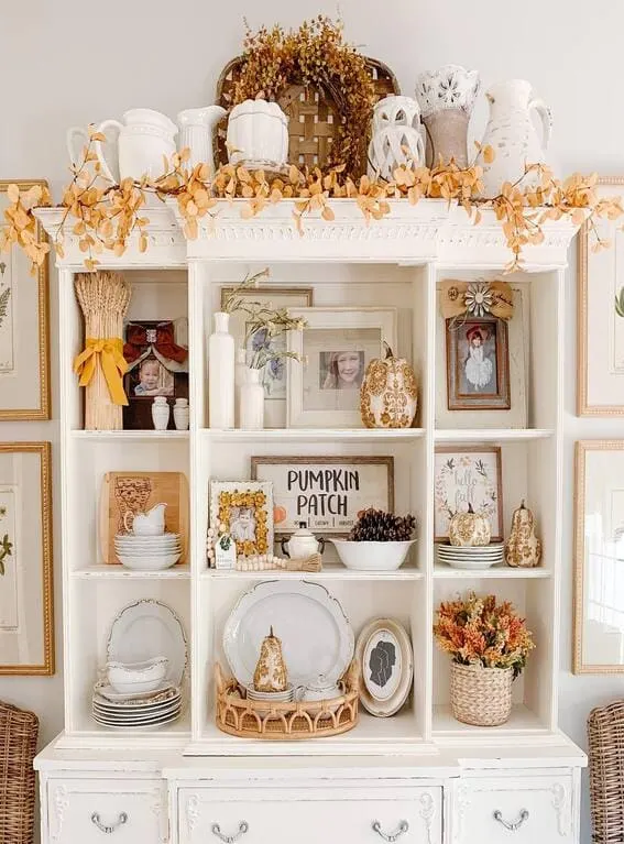 A charming hutch decorated with a golden leaf garland draped along the top, adding a soft, seasonal glow to the rustic display. 