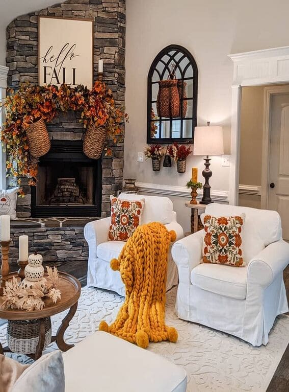 A cozy living room with a rustic stone fireplace, adorned with a cascading leaf garland in vibrant fall colors, bringing warmth and seasonal charm to the space. 