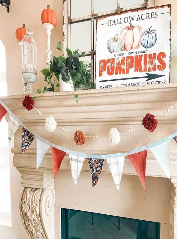 A festive fall mantel featuring a playful garland with colorful pennants and cozy pompoms, adding a whimsical touch to the seasonal decor. 