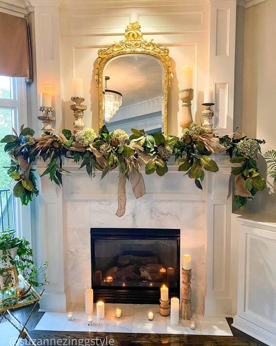 Elegant fall mantel with a lush magnolia garland and glowing candle display. 