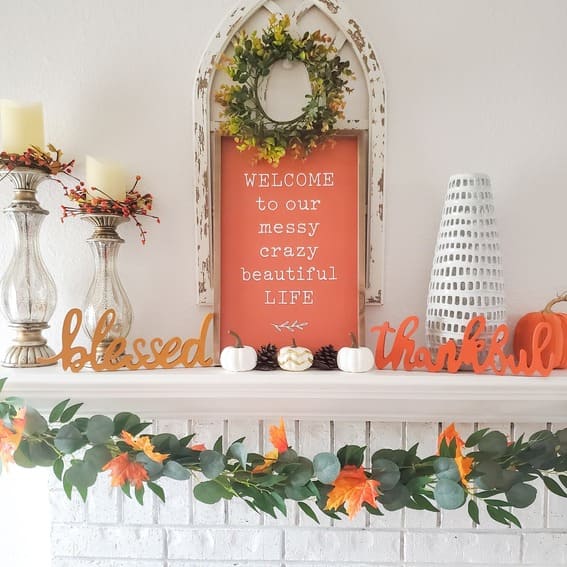 Fall mantel decor with bold orange details and autumn greenery. 