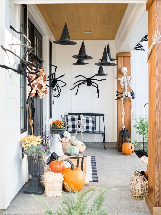 This porch creates a spooky yet inviting atmosphere with floating black witch hats hanging above and oversized spiders creeping along the walls. 