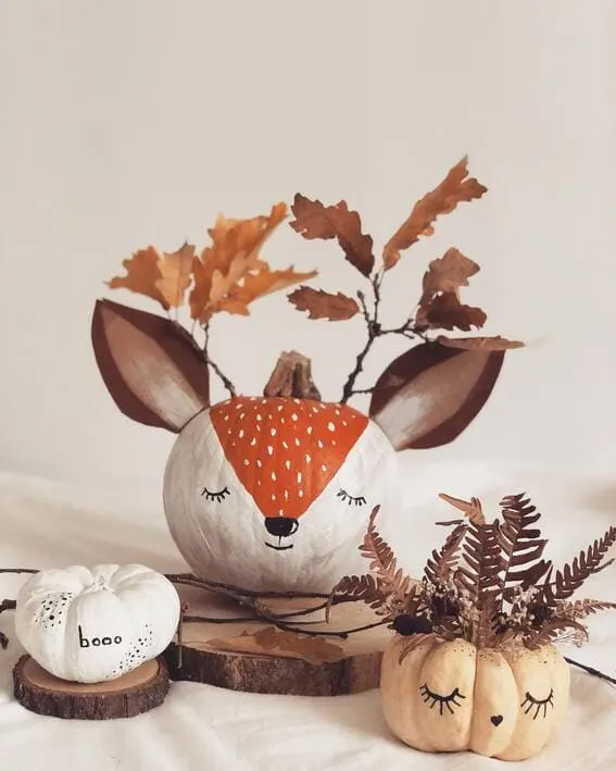 A playful woodland-themed pumpkin setup featuring a painted fox pumpkin and more miniature pumpkins with delicate hand-drawn details. 