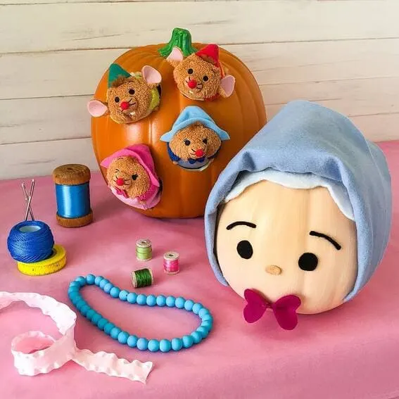 A charming Cinderella-themed pumpkin display featuring plush mice and a hand-painted pumpkin dressed as Cinderella—