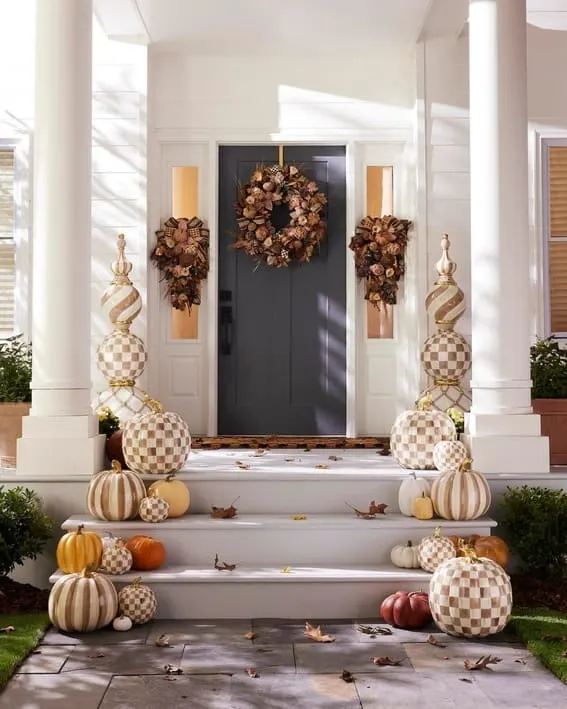 A grand entrance adorned with checkered pumpkins, striped gourds, and matching autumn wreaths. 