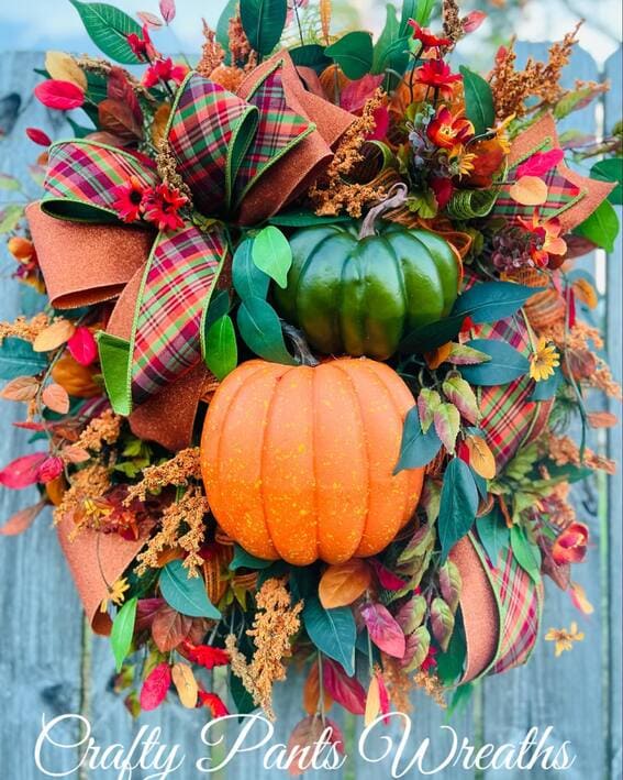 A vibrant wreath featuring bold green and orange pumpkins paired with plaid ribbons and rich autumn florals. 