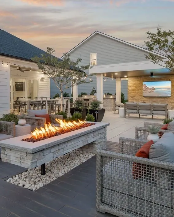 Modern backyard featuring a linear fire pit, surrounded by comfortable seating and a beautiful white rock. 